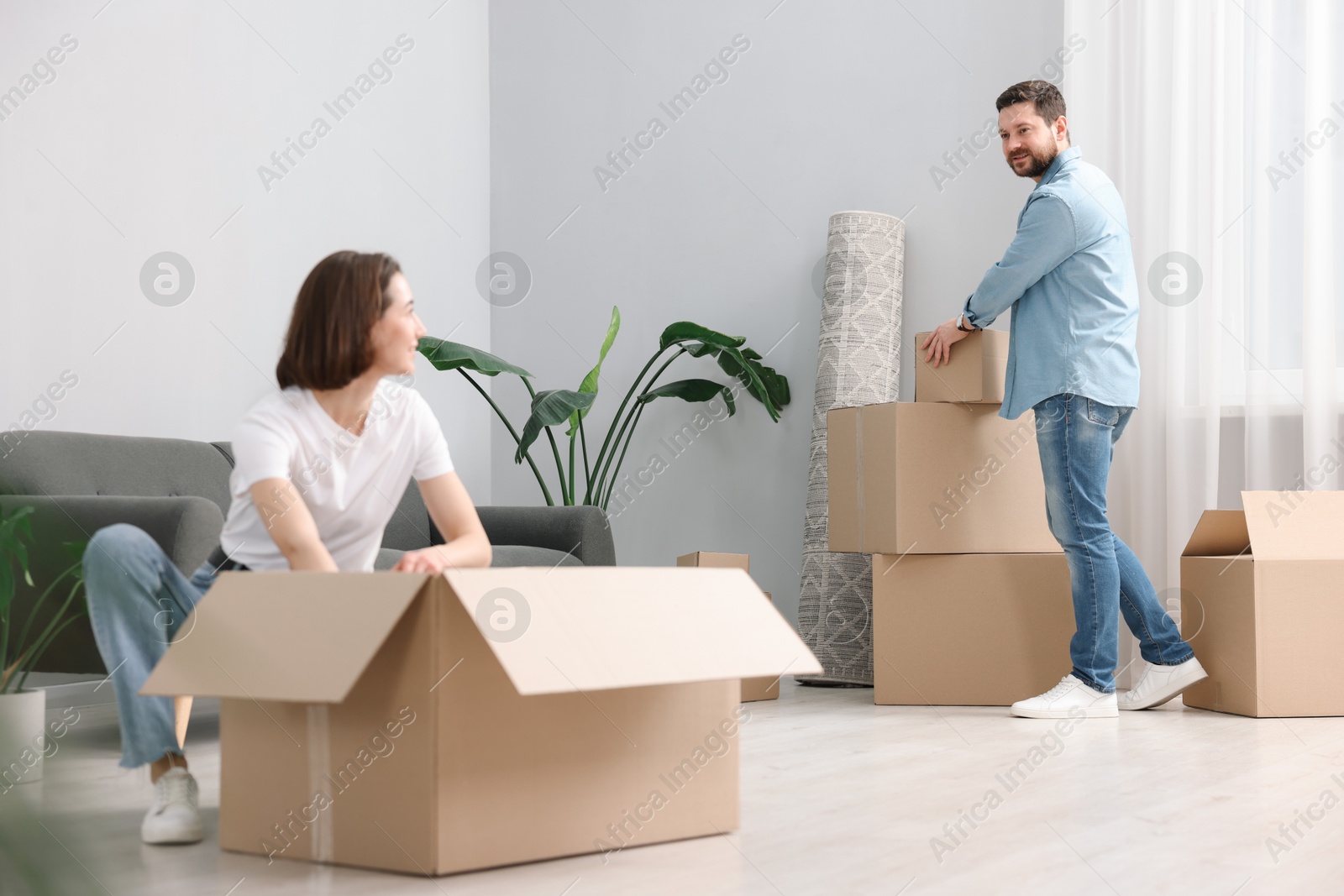 Photo of Moving day. Happy couple unpacking their belongings in new home, selective focus