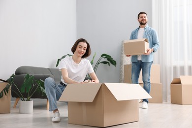 Photo of Moving day. Happy couple unpacking their belongings in new home, selective focus