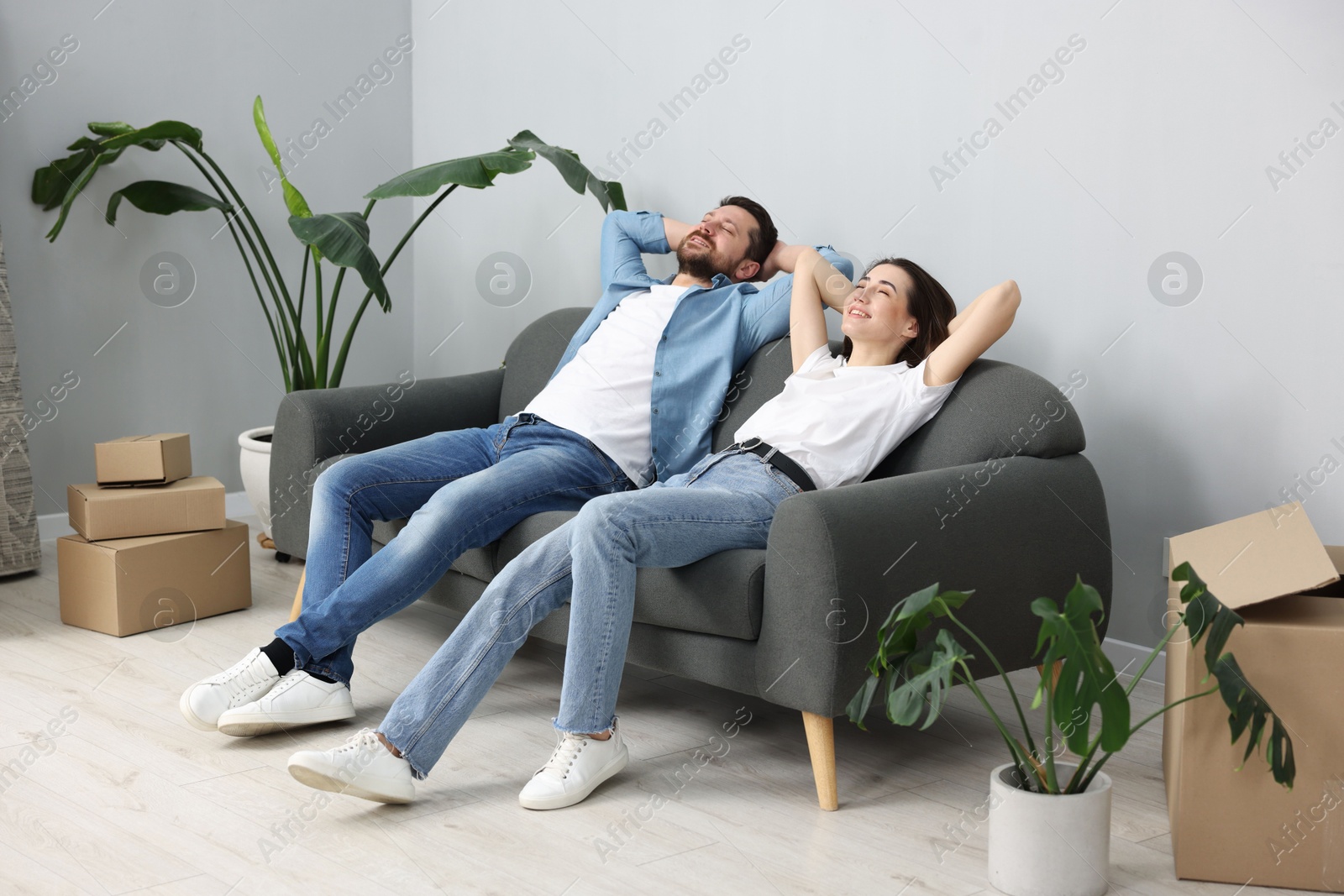 Photo of Moving day. Happy couple resting on couch in their new home