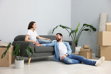 Moving day. Happy couple resting on couch in their new home