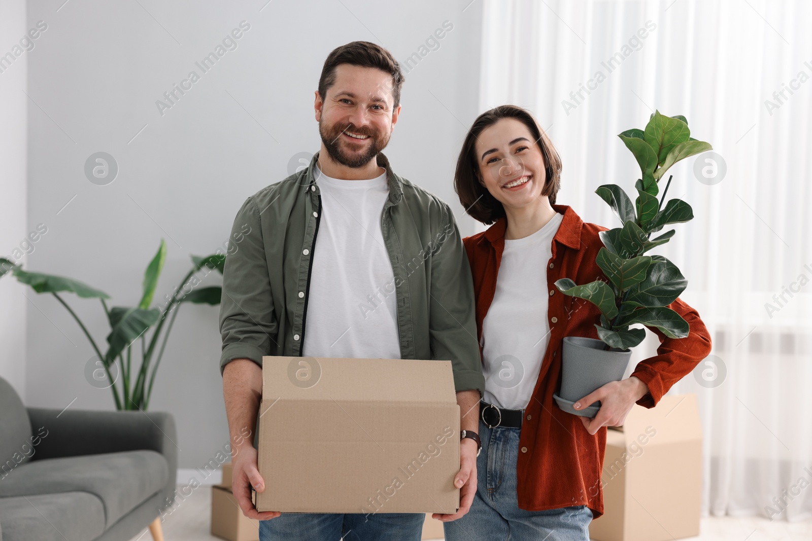 Photo of Moving day. Happy couple with their belongings in new home