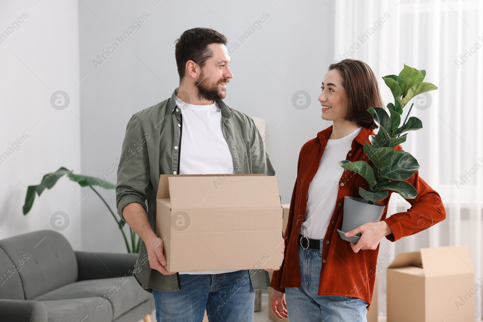 Photo of Moving day. Happy couple with their belongings in new home