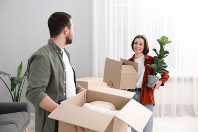 Photo of Moving day. Happy couple with their belongings in new home, selective focus