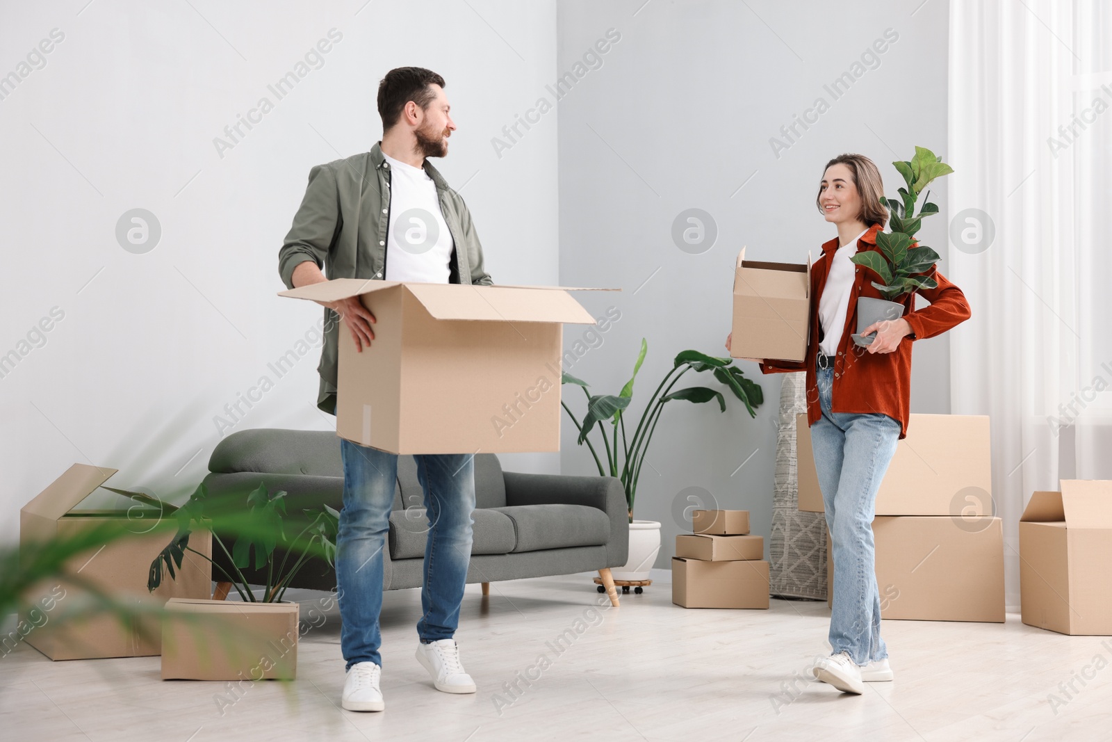 Photo of Moving day. Happy couple with their belongings in new home