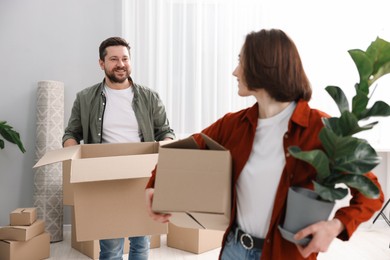 Photo of Moving day. Happy couple with their belongings in new home, selective focus