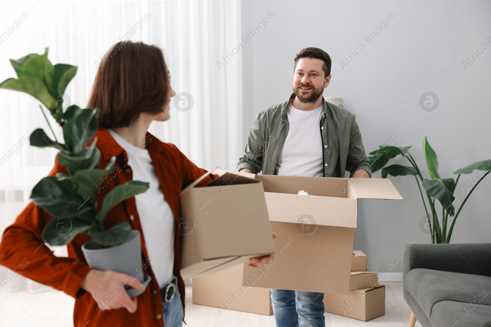 Photo of Moving day. Happy couple with their belongings in new home, selective focus