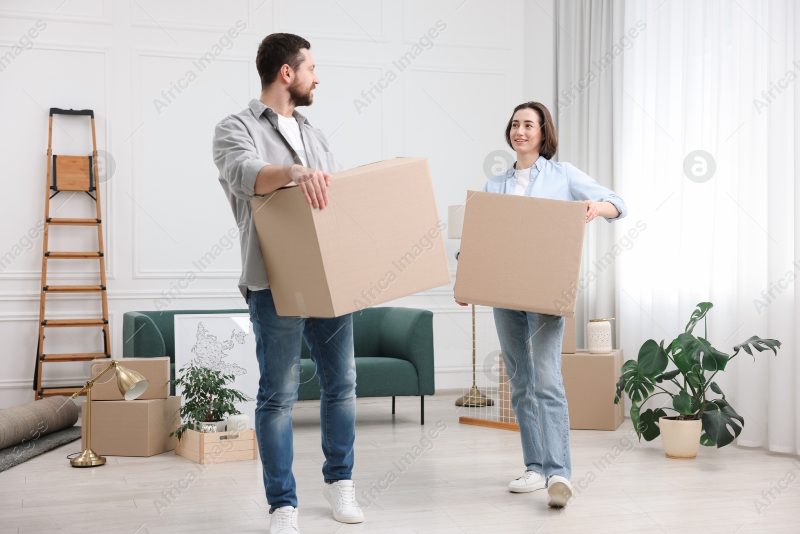 Photo of Moving day. Happy couple with cardboard boxes in their new home