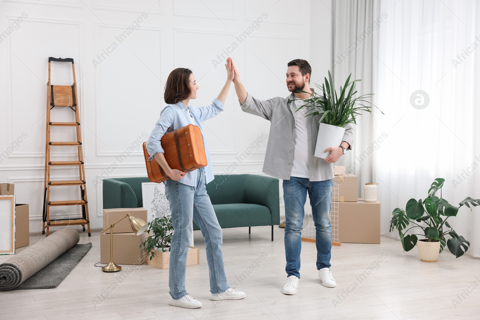 Photo of Moving day. Happy couple giving each other high five in their new home