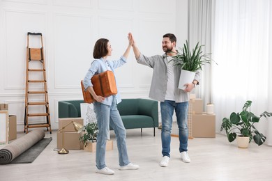 Photo of Moving day. Happy couple giving each other high five in their new home