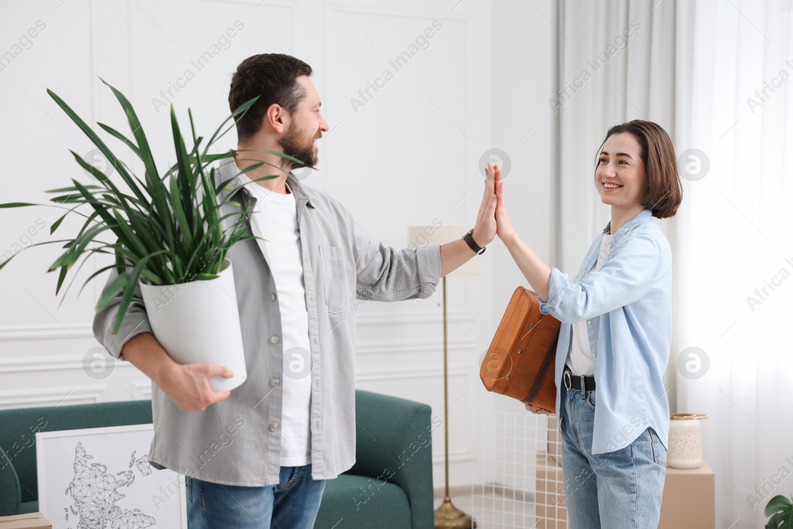 Photo of Moving day. Happy couple giving each other high five in their new home