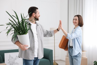 Photo of Moving day. Happy couple giving each other high five in their new home