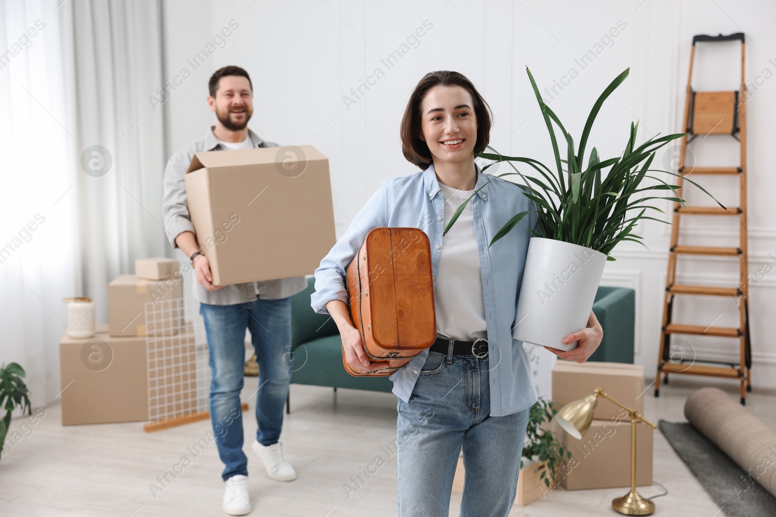 Photo of Moving day. Happy couple with their belongings in new home, selective focus