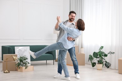 Photo of Moving day. Happy couple dancing in their new home