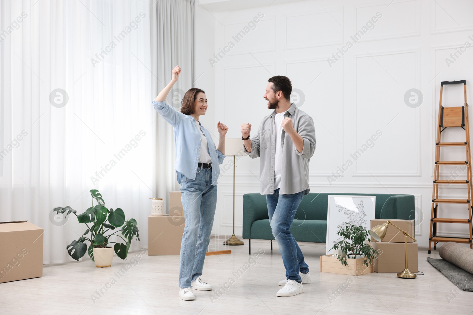 Photo of Moving day. Happy couple dancing in their new home