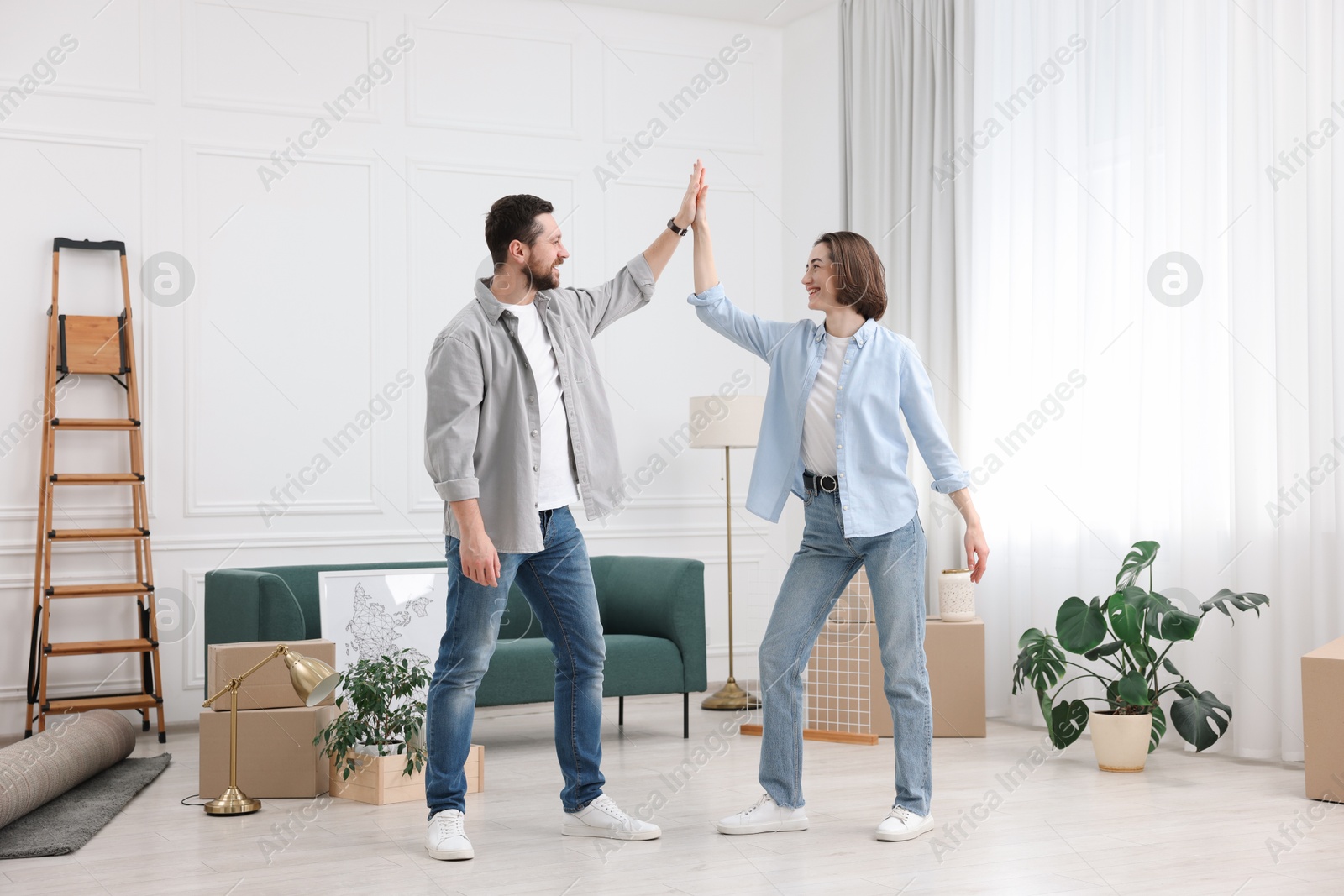 Photo of Moving day. Happy couple dancing in their new home