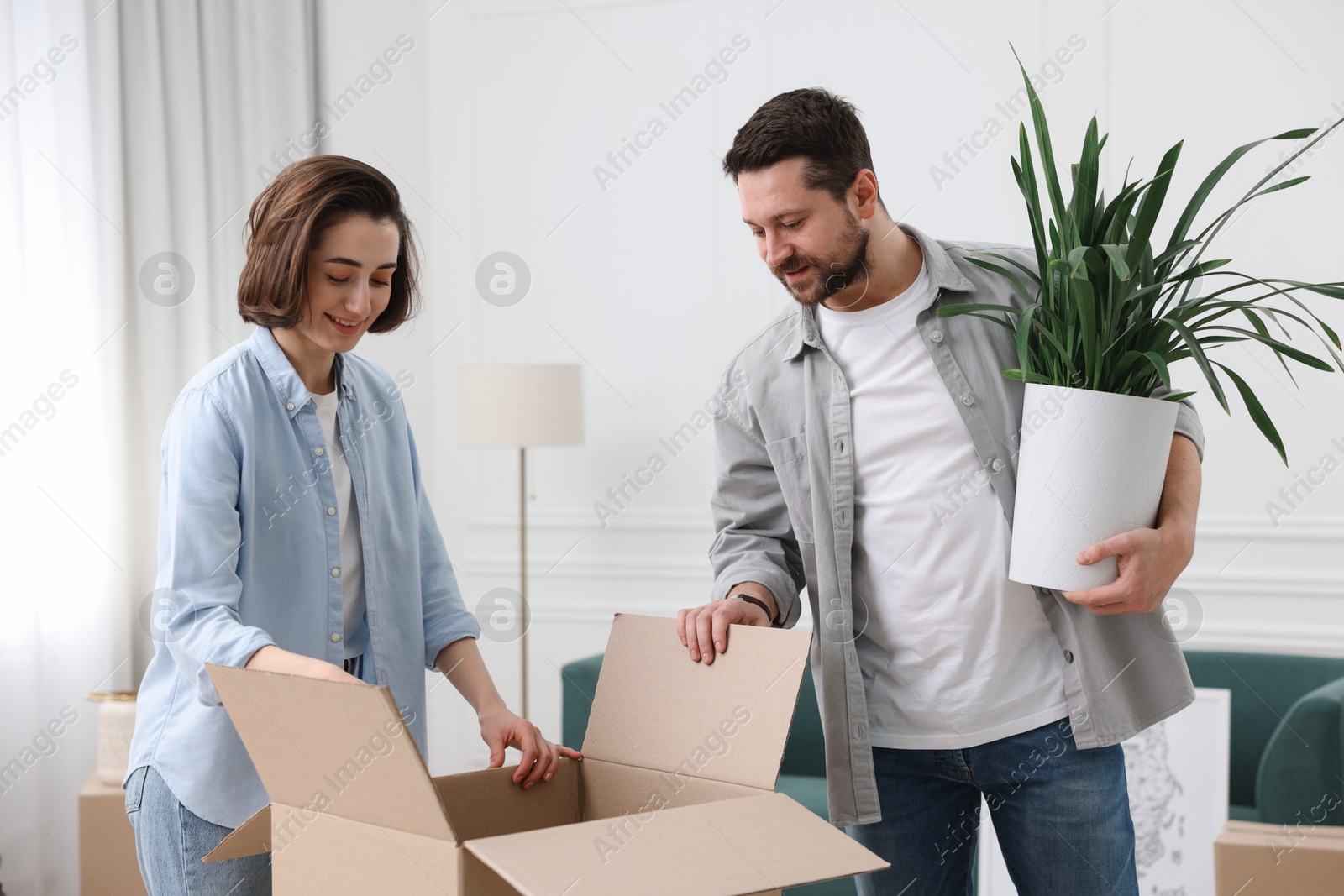 Photo of Moving day. Happy couple unpacking their belongings in new home