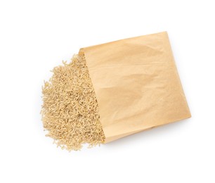 Photo of Raw brown rice in paper bag isolated on white, top view