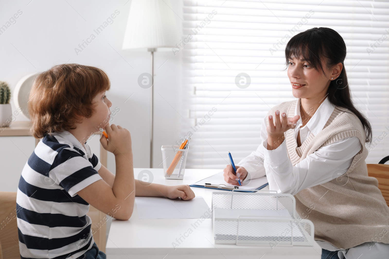 Photo of Little boy having consultation with psychologist in office