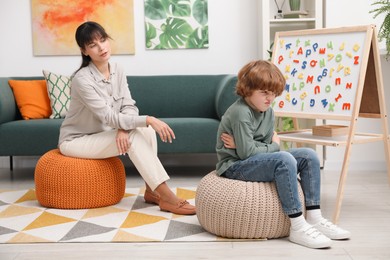 Photo of Psychologist having session with stubborn little boy in office