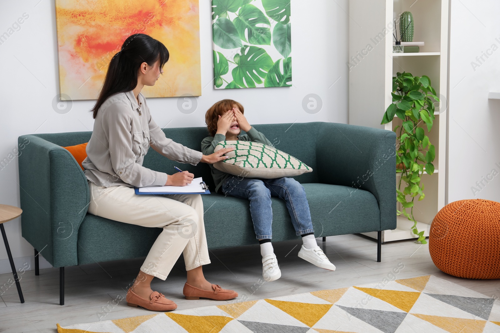 Photo of Upset little boy having therapy session with psychologist in office