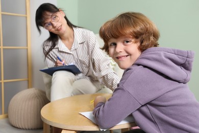 Photo of Psychologist evaluating boy's cognitive functions in office, selective focus