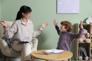 Photo of Psychologist evaluating boy's cognitive functions in office