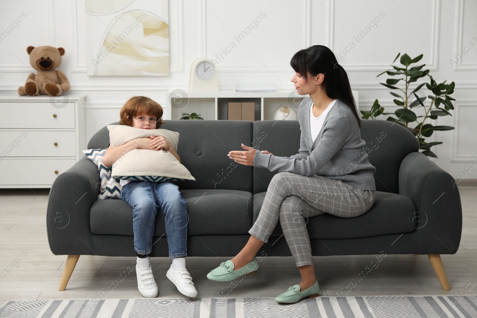 Photo of Scared little boy having therapy session with psychologist in office