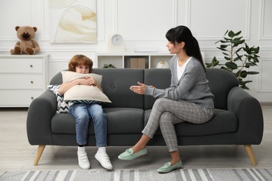 Scared little boy having therapy session with psychologist in office