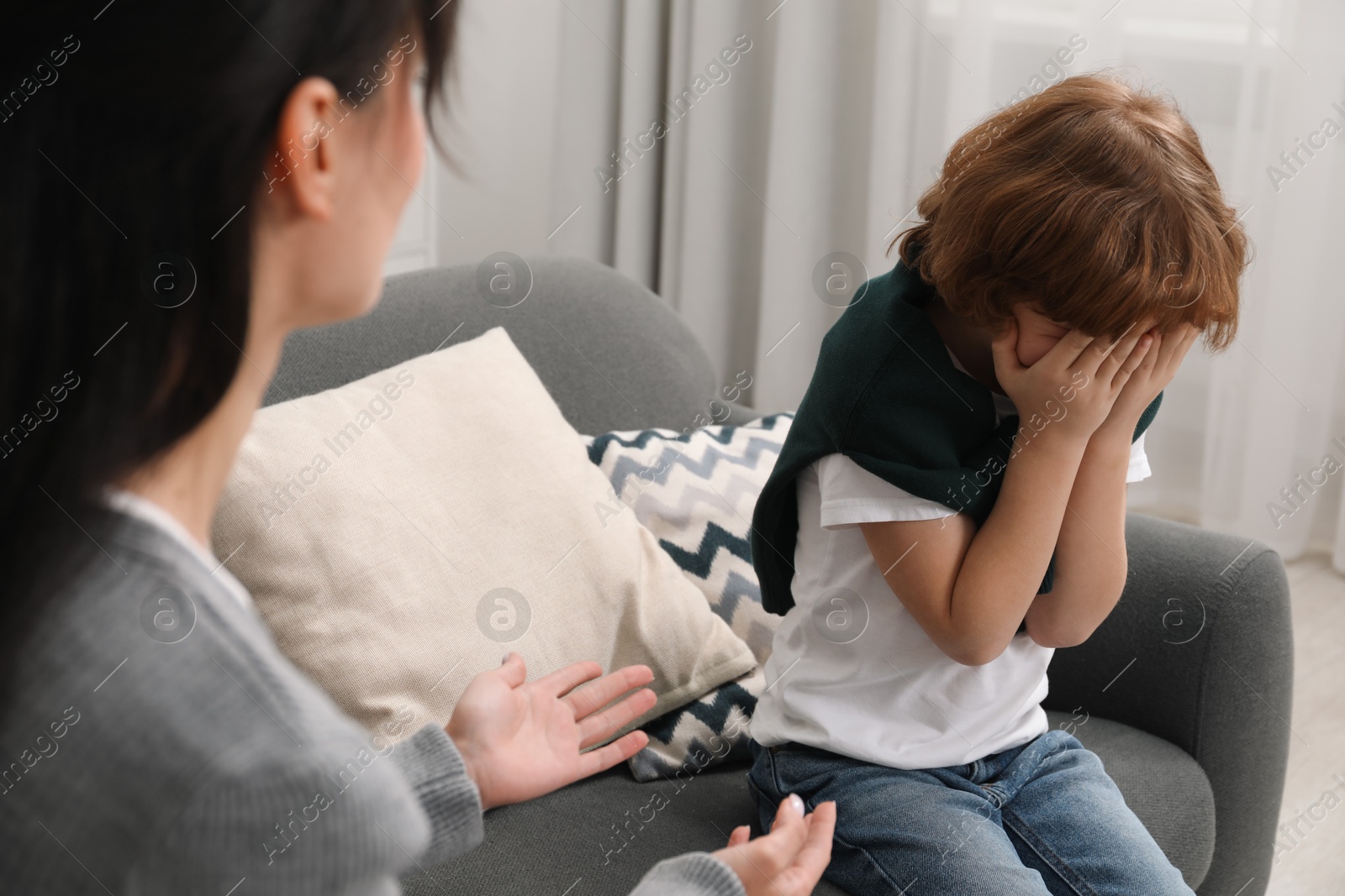 Photo of Upset little boy having therapy session with psychologist in office