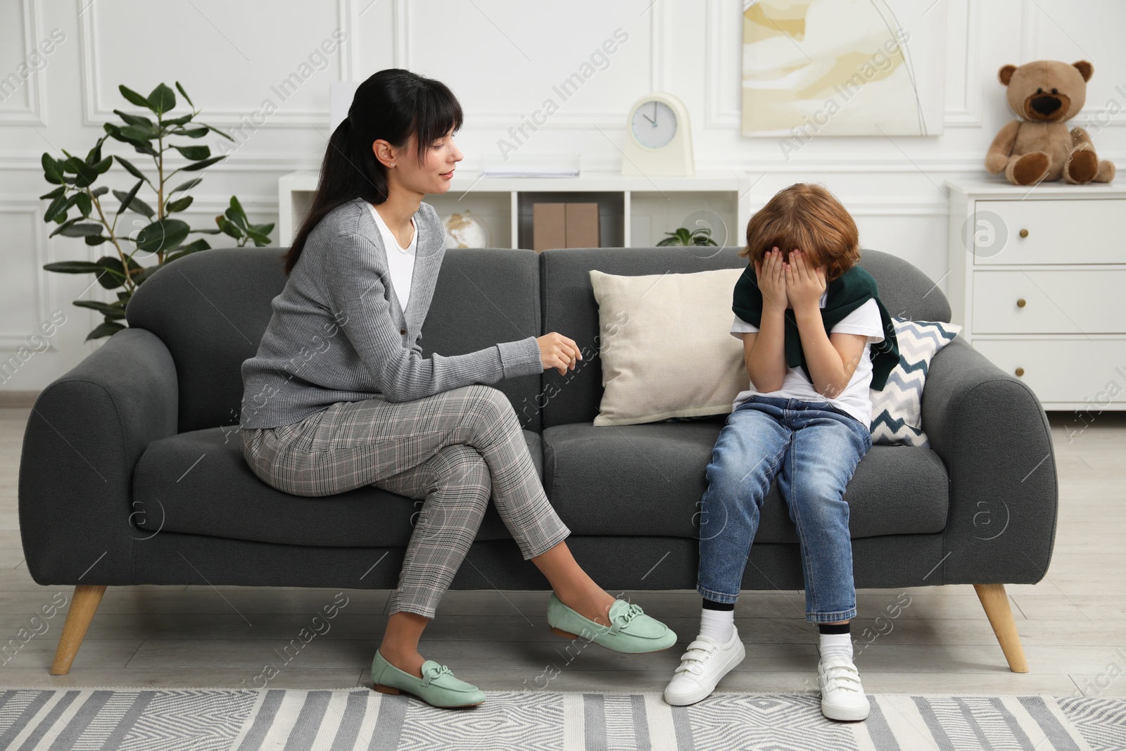 Photo of Upset little boy having therapy session with psychologist in office