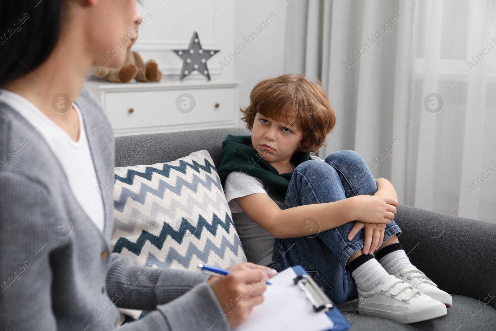 Photo of Little boy having therapy session with psychologist in office