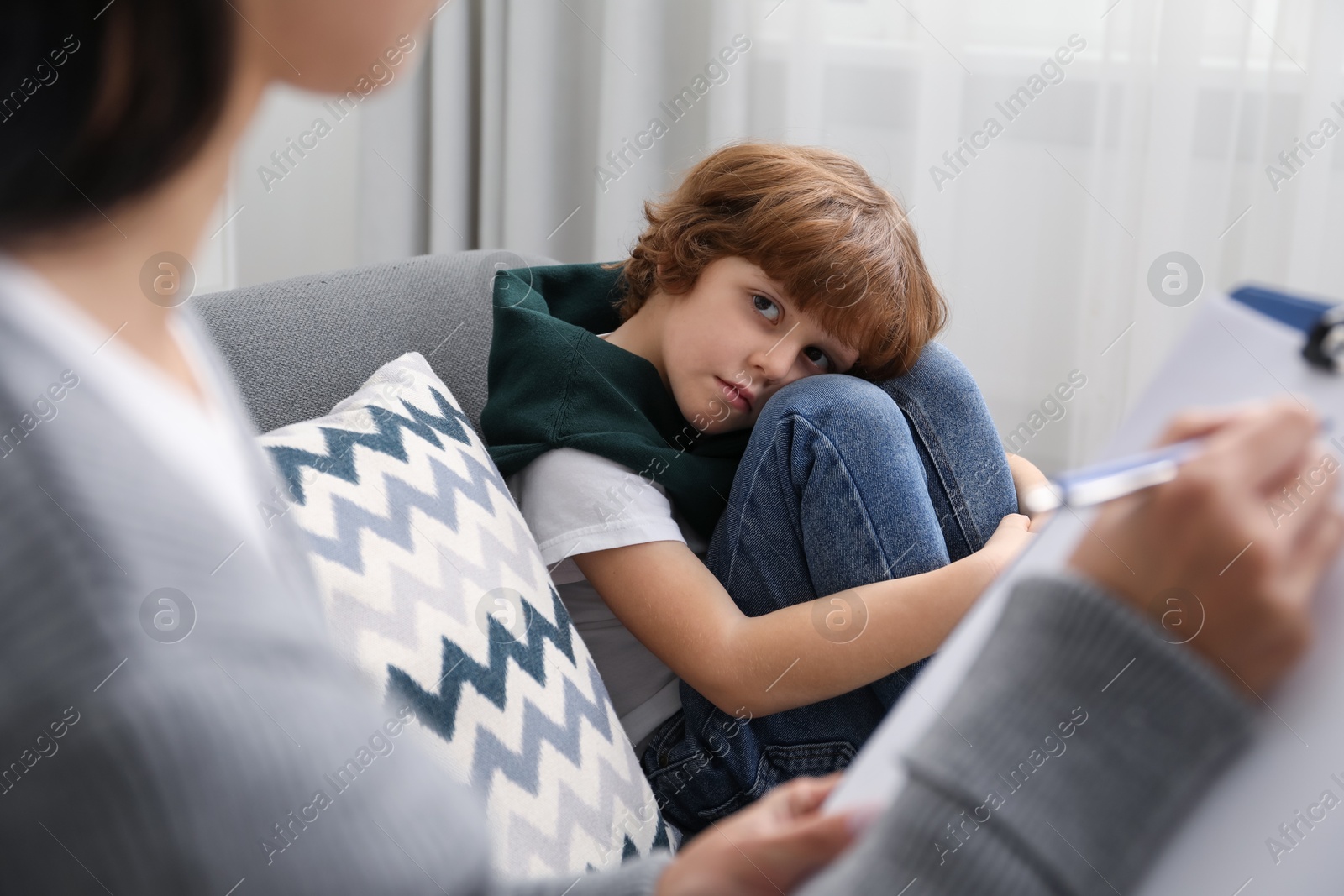 Photo of Little boy having therapy session with psychologist in office