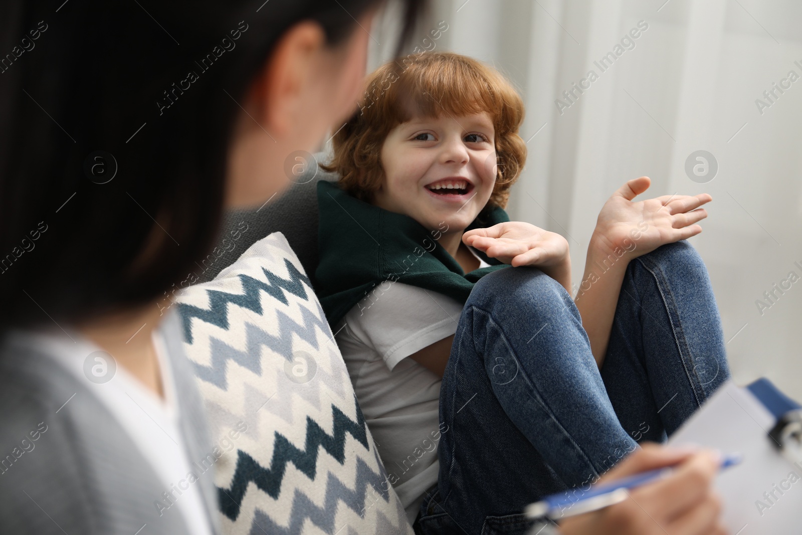 Photo of Little boy having therapy session with psychologist in office