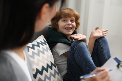 Photo of Little boy having therapy session with psychologist in office