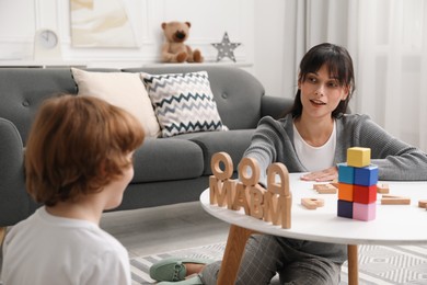 Photo of Psychologist evaluating boy's cognitive functions at table in office, selective focus