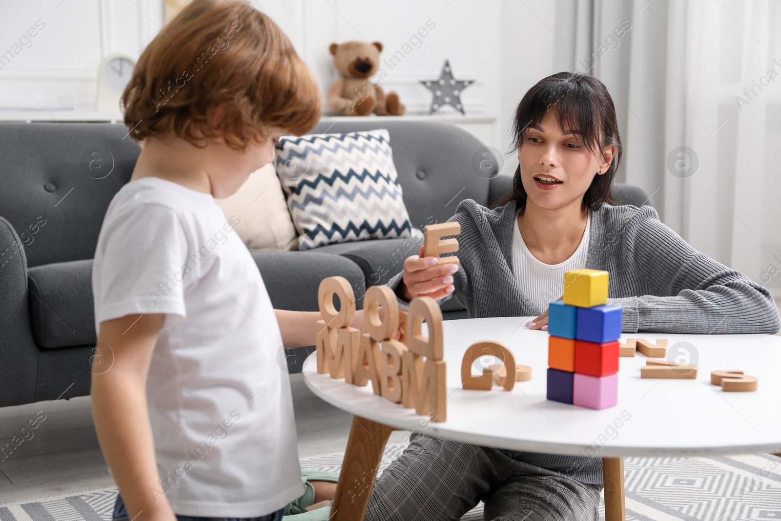 Photo of Psychologist evaluating boy's cognitive functions at table in office, selective focus