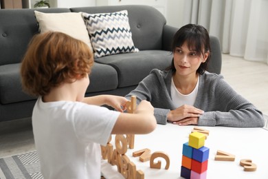 Photo of Psychologist evaluating boy's cognitive functions at table in office, selective focus