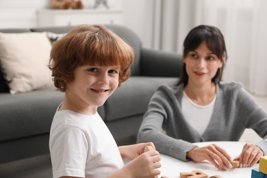 Photo of Psychologist evaluating boy's cognitive functions at table in office, selective focus