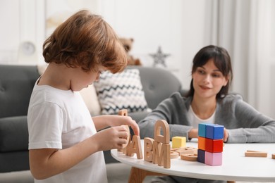 Photo of Psychologist evaluating boy's cognitive functions at table in office, selective focus