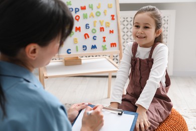 Photo of Little girl having consultation with psychologist in office