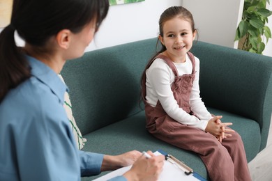 Photo of Little girl having consultation with psychologist in office