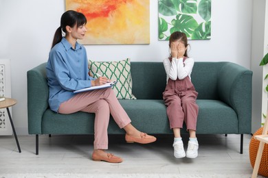 Photo of Upset girl having consultation with psychologist in office