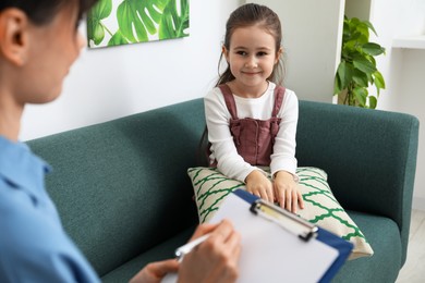 Photo of Little girl having consultation with psychologist in office