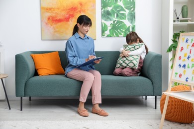 Photo of Psychologist comforting little girl during therapy session indoors