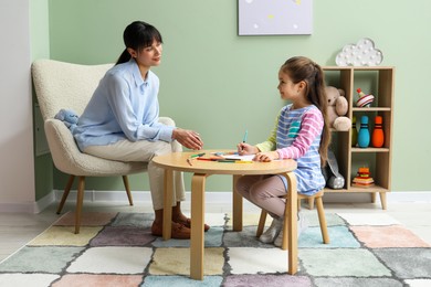 Photo of Little girl drawing during psychological evaluation in office