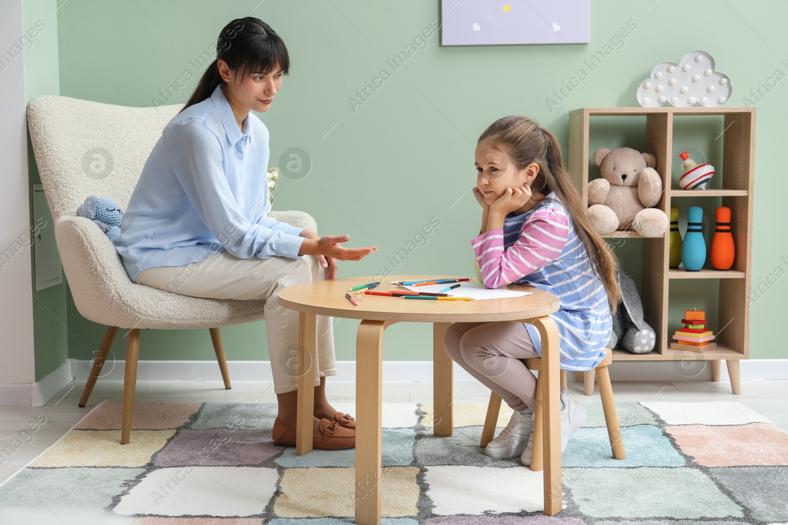 Photo of Psychologist having consultation with stubborn girl indoors