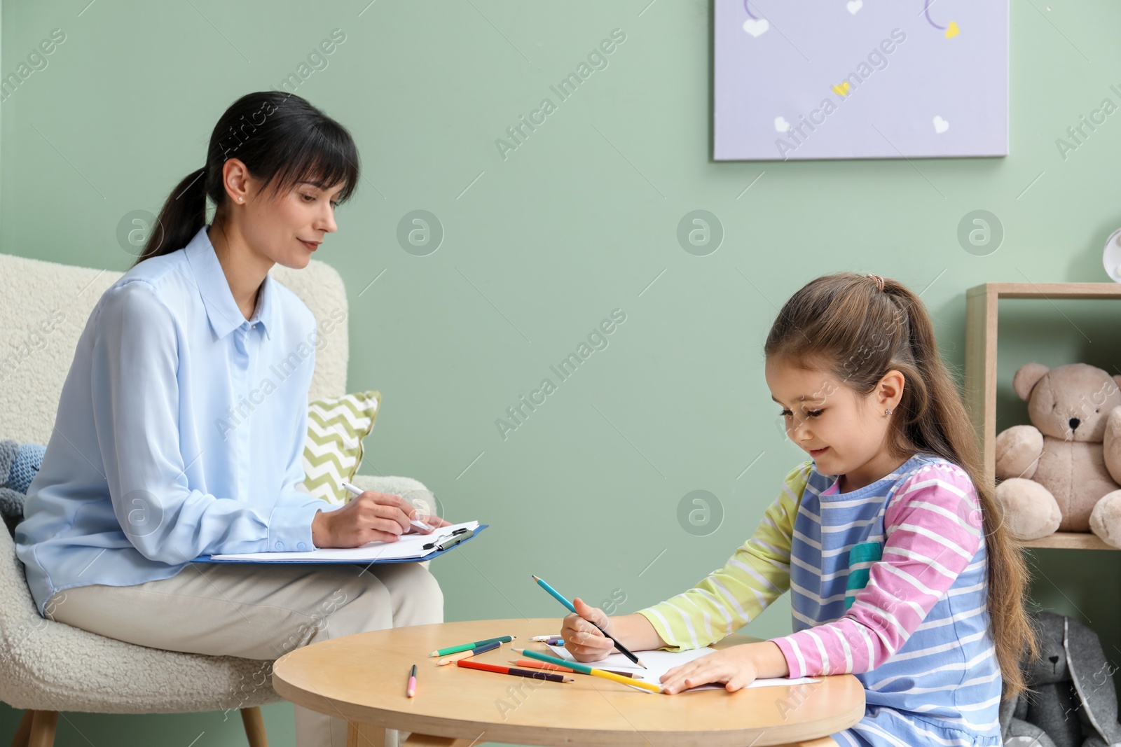 Photo of Little girl drawing during psychological evaluation in office