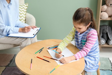 Photo of Little girl drawing during psychological evaluation in office