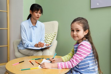 Photo of Little girl drawing during psychological evaluation in office