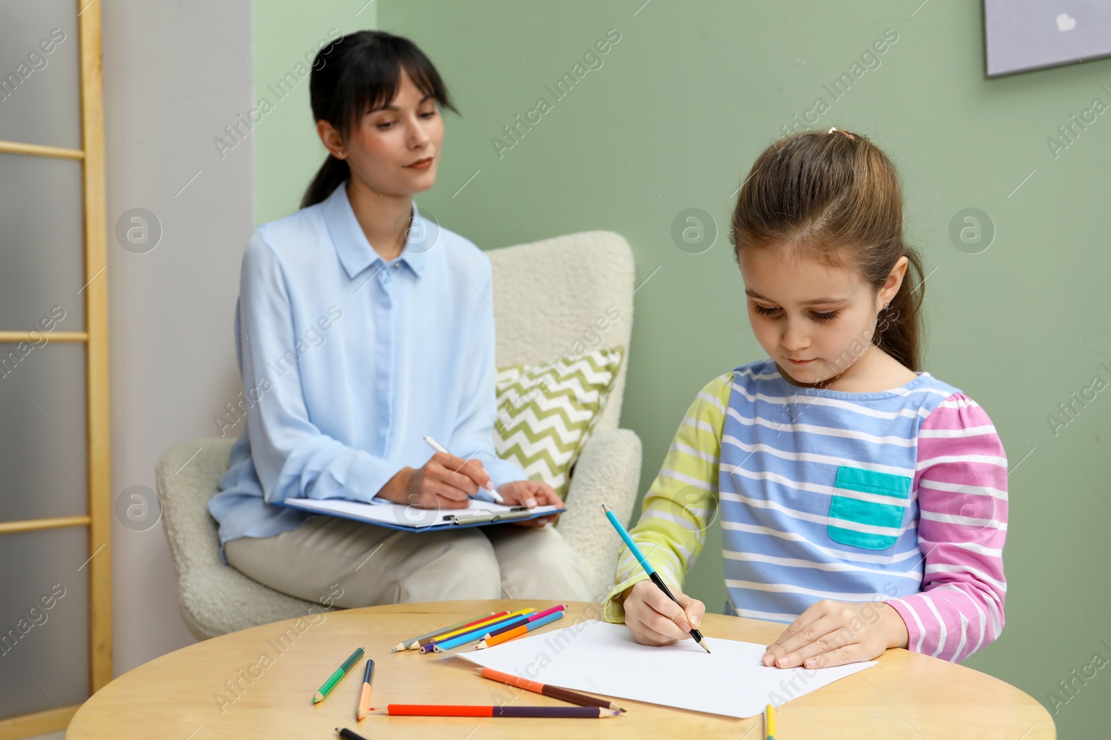 Photo of Little girl drawing during psychological evaluation in office